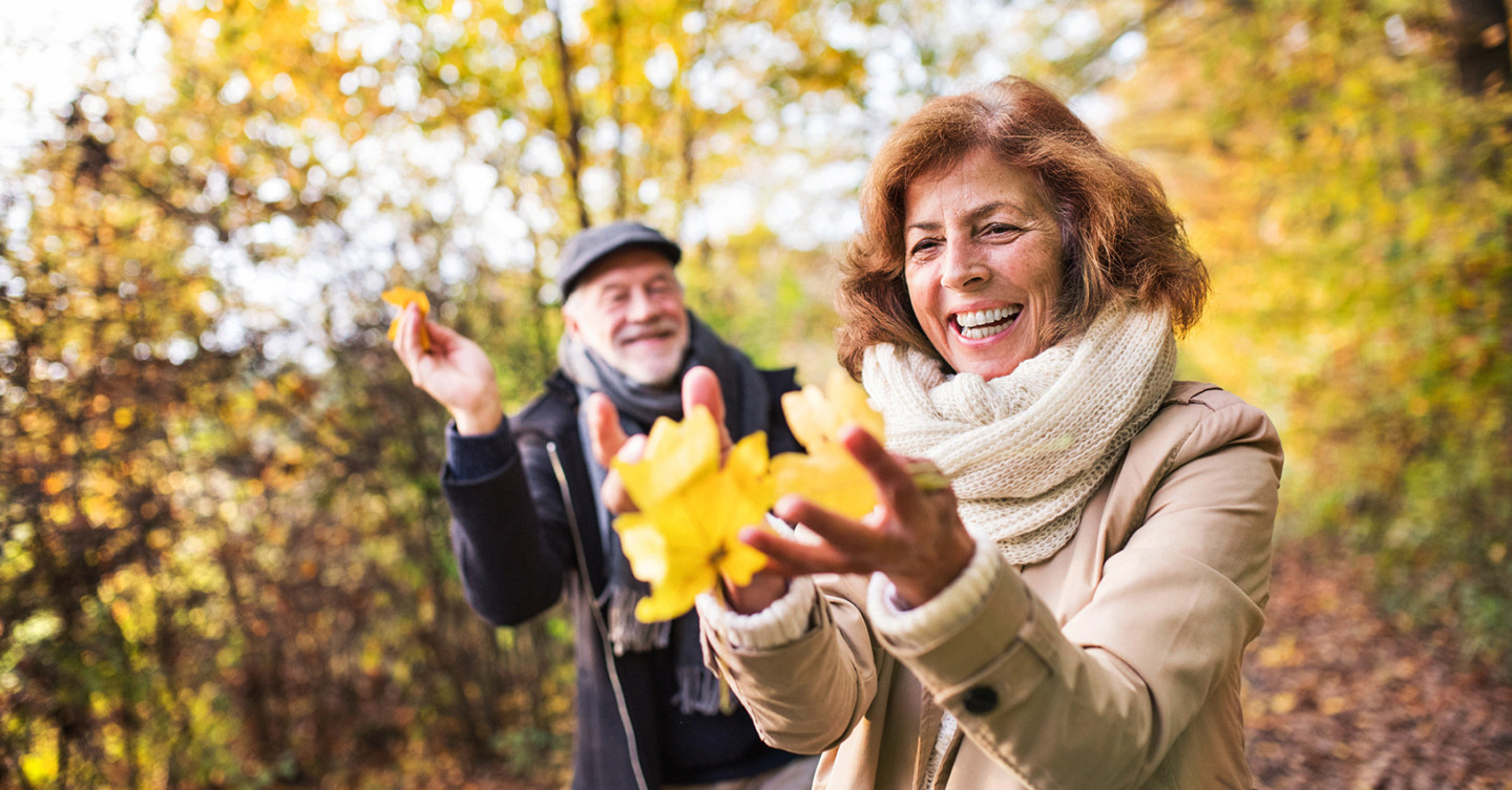 Happy seniors playing with leaves