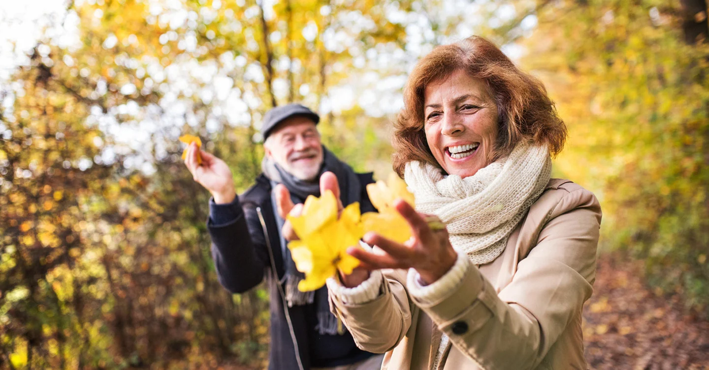 Happy seniors playing with leaves