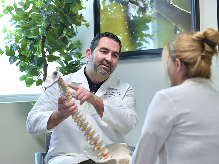 physician showing patient spine model