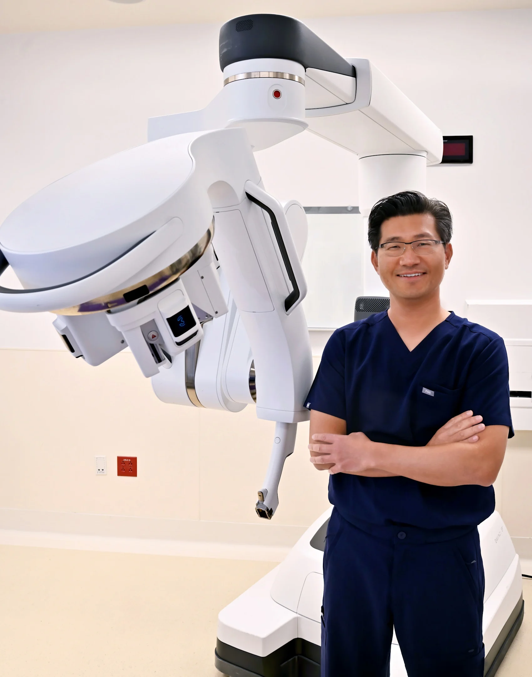 Dr. Moses Kim posing next to a surgical machine