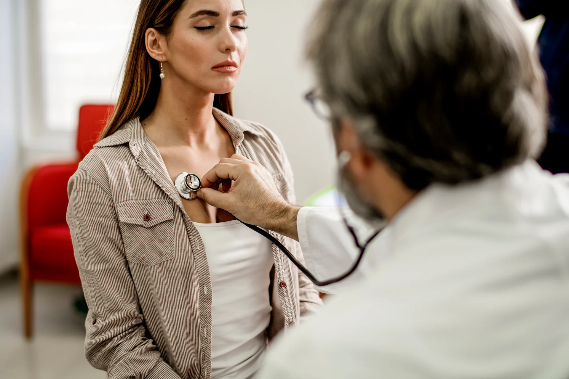 Doctor listening to woman with stethoscope
