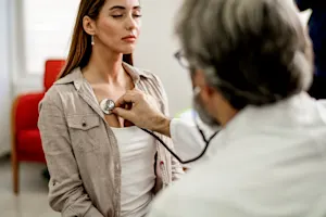 Doctor listening to woman with stethoscope
