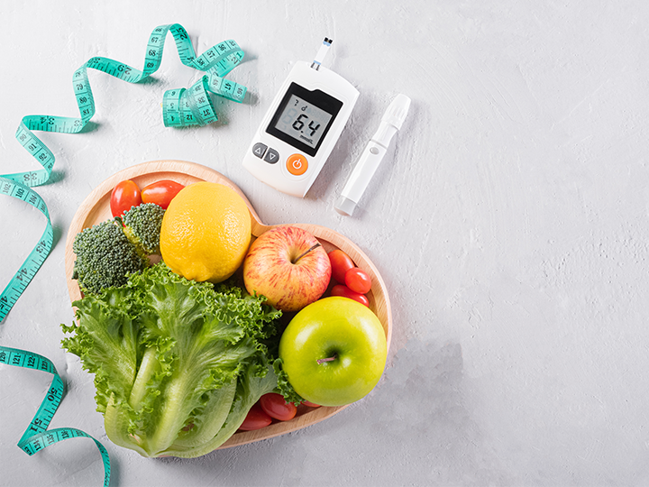 A plate of healthy food, measuring tape, and a blood sugar monitor