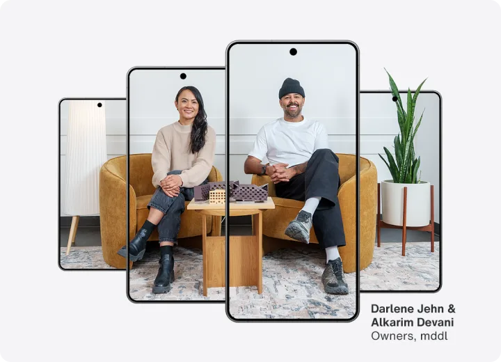 Four phones lined up in a row with an image of two business owners sitting spanning all four phones.