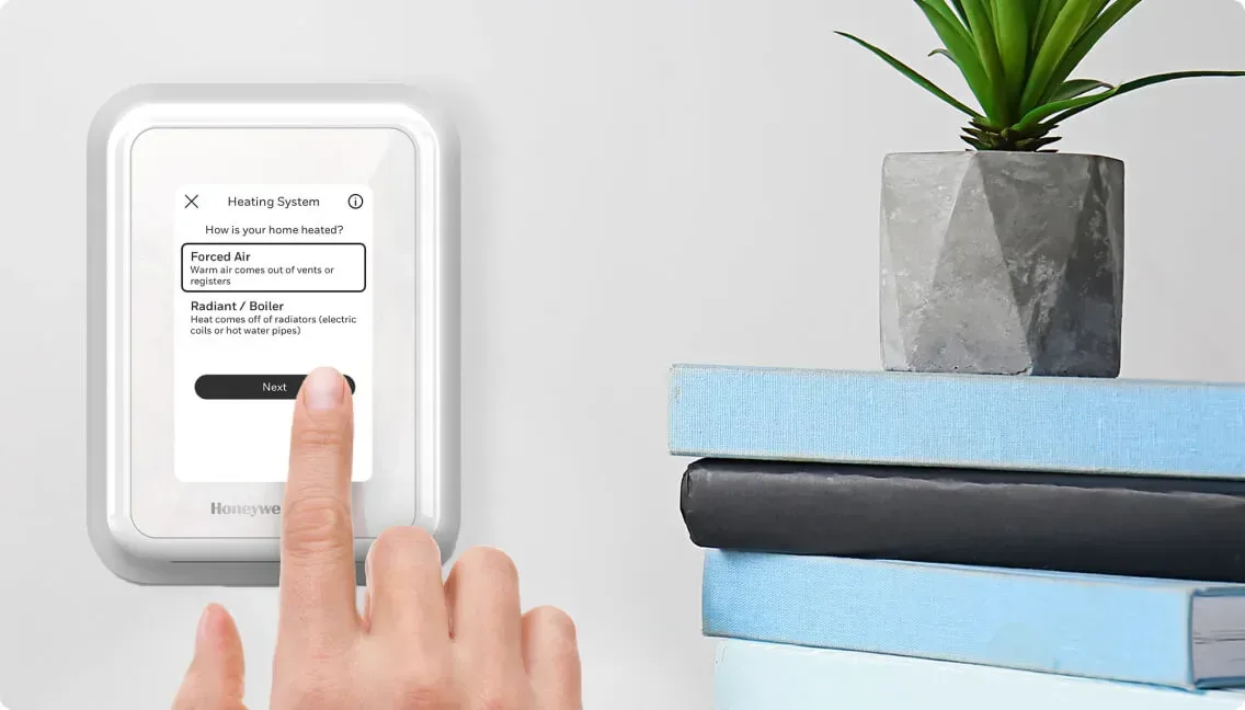 Main appuyant sur le bouton Suivant de l'écran de configuration du système de chauffage du thermostat intelligent Honeywell