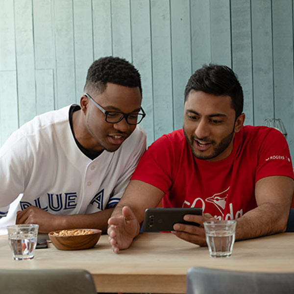 Friends watching a Blue Jays game on their phone while in restaurant