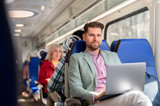 Man werkt op laptop in een trein.