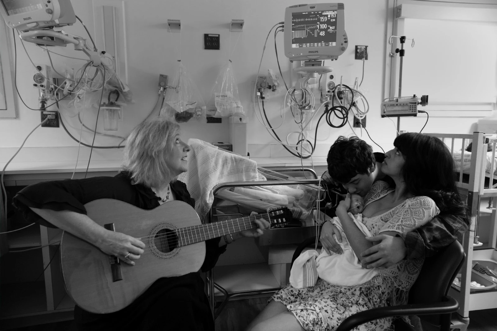 Joanne Loewy, DA, LCAT, MT-BC, left, Professor of Medicine at the Icahn School of Medicine at Mount Sinai, plays during a family music therapy session at Mount Sinai's Neonatal Intensive Care Unit. She is co-leader of a project with Rachel Reed, MD, Assistant Professor in the Division of Newborn Medicine, to explore the impact of music on the respiratory function of preterm babies.