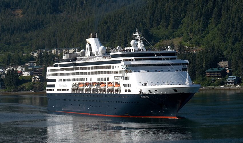 Holland America Line - Cruise ship with town on a green mountain side in the background.