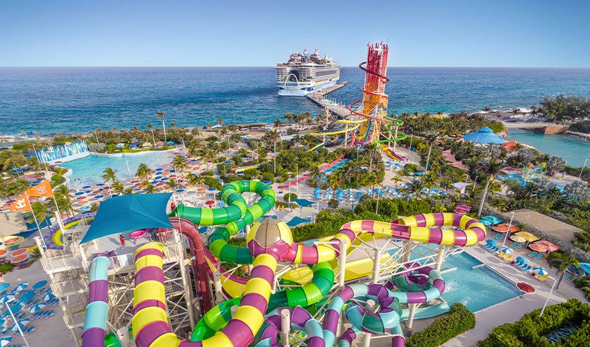 Royal Caribbean® - Aerial view of a cruise ship docked next to an oceanside amusement park