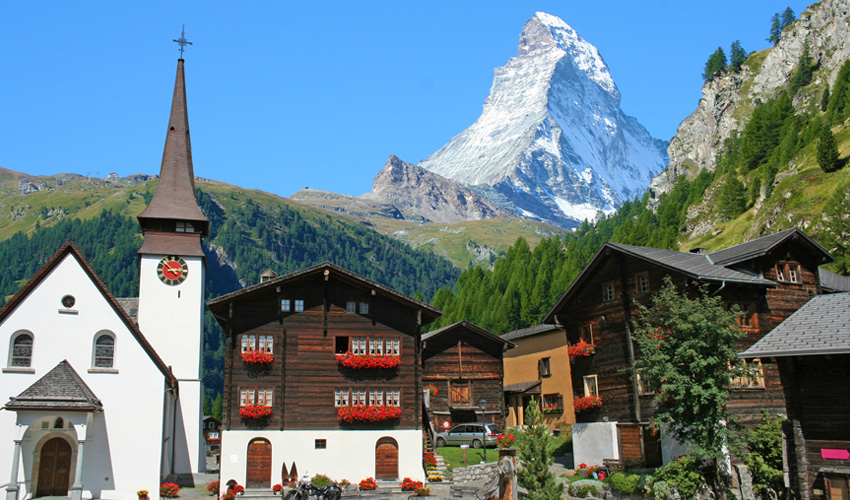 A picturesque alpine village set against the backdrop of the Matterhorn mountain on a sunny day.