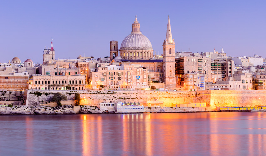 Stunning waterfront view of Valetta, Malta, showcasing the grand cathedral at sunset.