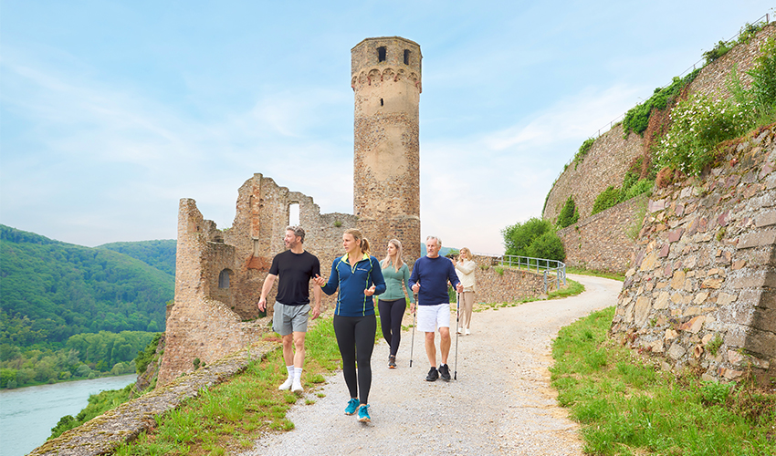 AmaWaterwaysTM - Group of tourists walking past ancient ruins of a riverside stone castle