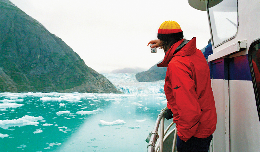 Extraordinary Explorations® - Man photographing a glacier from the deck of a cruise ship