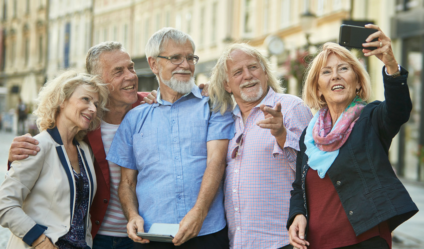 A group of older adults taking a selfie together on a lively city street.