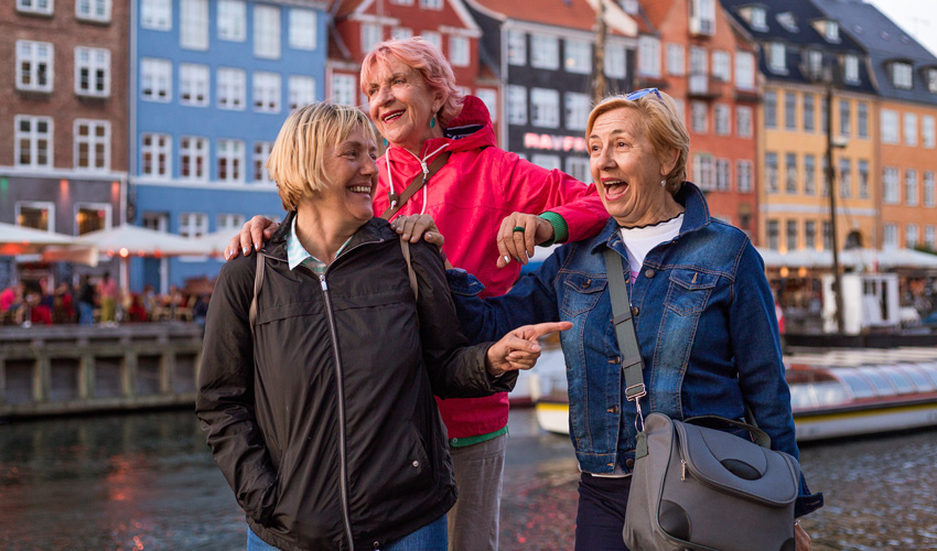 Three women laughing and enjoying a walk along a colourful canal.