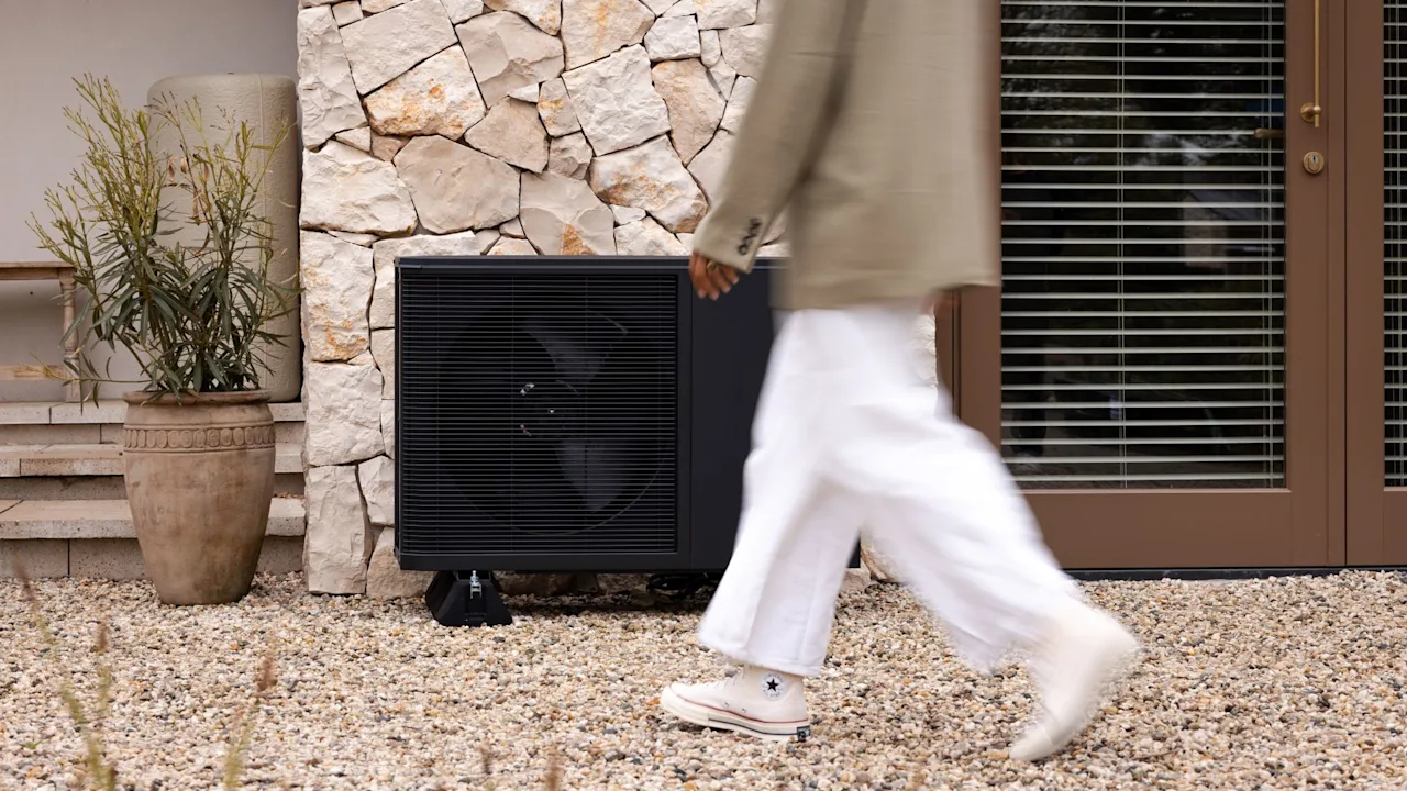 Flint weheat warmtepomp klein naast een huis met een persoon die voor de foto langsloopt