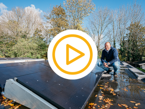 man hurkend op dak met zonnepanelen en video play button