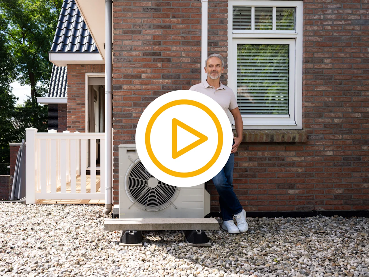 Mn poserend naast een warmtepomp op dak van de eerste verdieping met video play button