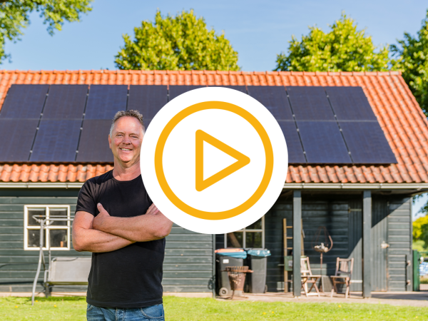 lachende klant met armen over elkaar met op de achtergrond een grote schuur vol met zonnepanelen en een video play button