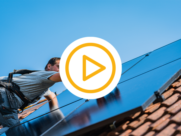 Saman monteur op een schuin dak met dakpannen installeert zonnepanelen