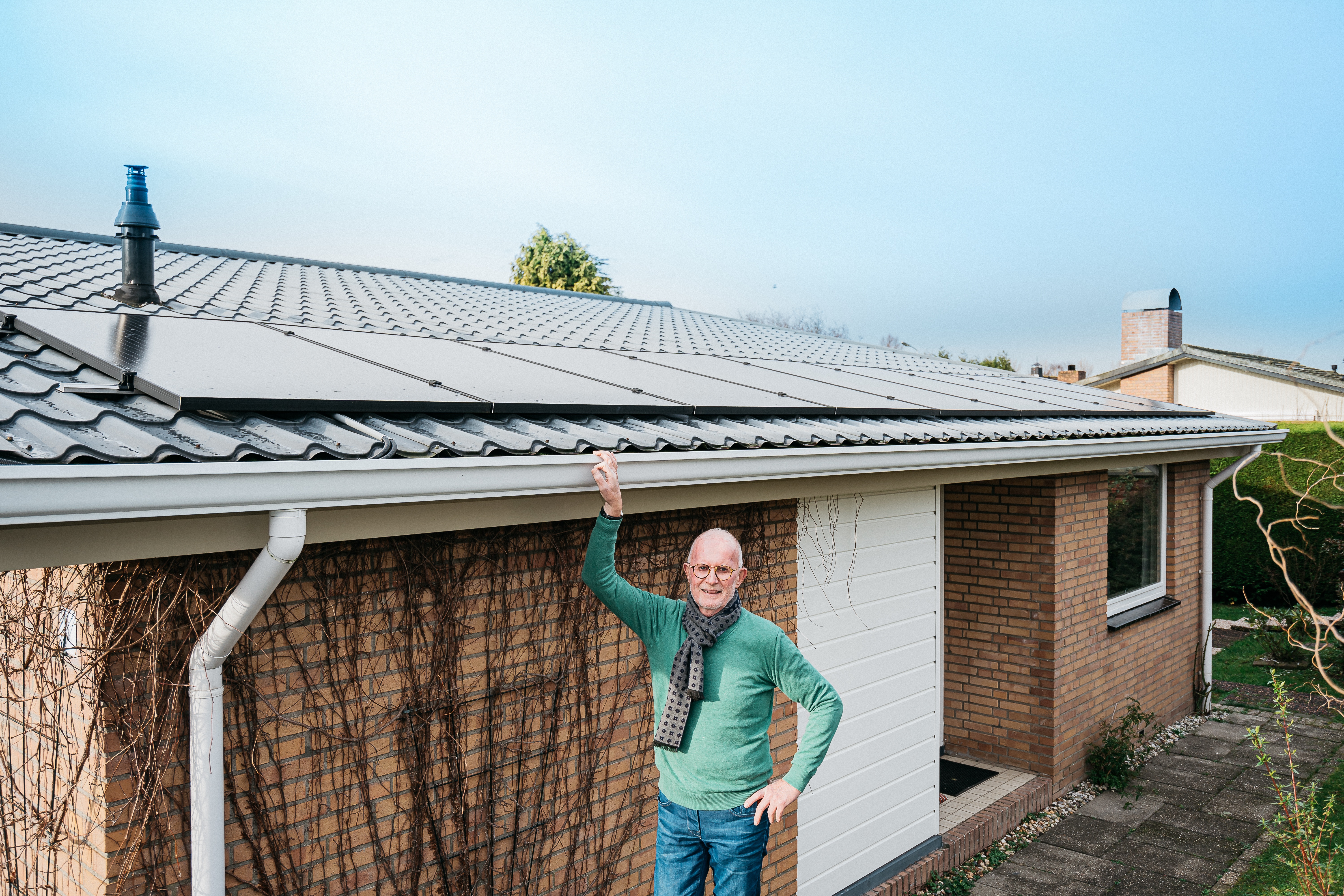 Man met zonnepanelen op schuin dak