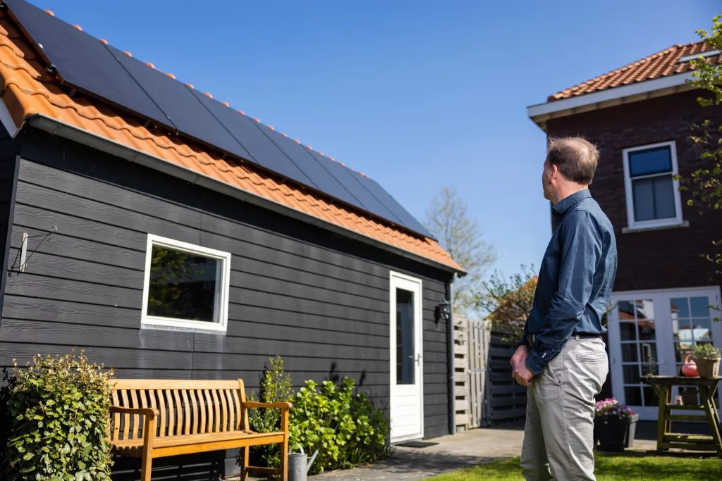 Klant kijkt trots naar zijn moderne schuur met zonnepanelen op het dak
