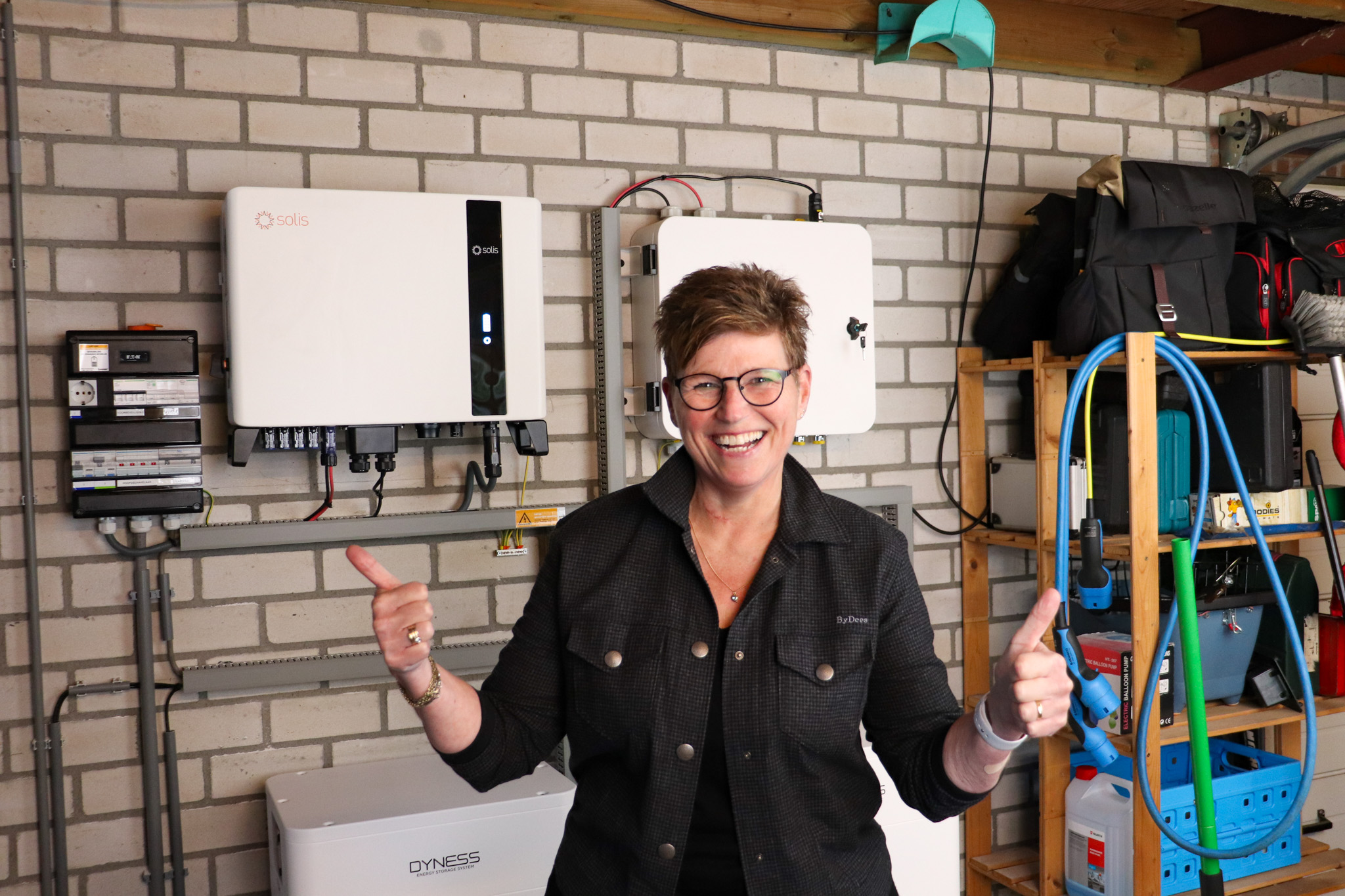 Lachende klant met 2 duimen omhoog die blij is met haar thuisbatterijen installatie
