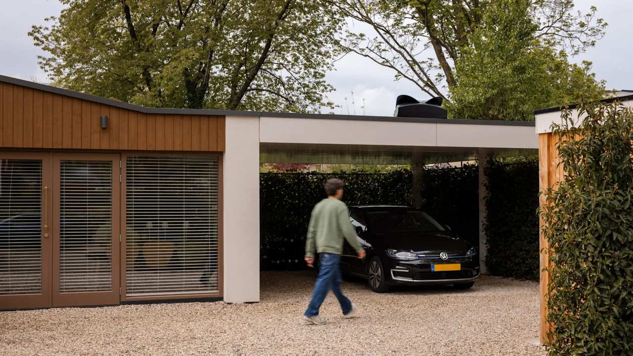 Blackbird Weheat warmtepomp op het dak van een carport in een tuin boven een volkswagen met een man die langsloopt door de tuin