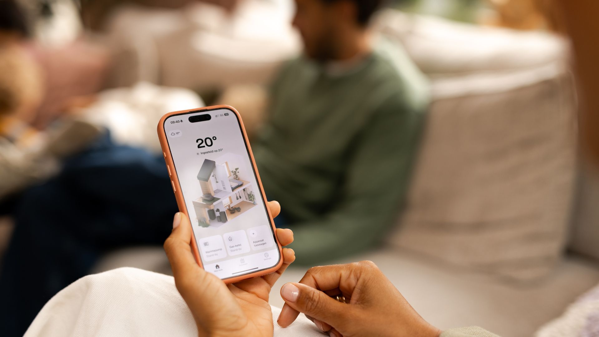 Persoon die de telefoon app van Weheat bekijkt op een gezellig bijeenkomst in huis