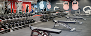 Fresh Fitness treningssenter med fokus på billig trening. Bilde av manualsone med treningsutstyr og frivekter, ideelt for styrketrening i et moderne og rimelig treningsmiljø.