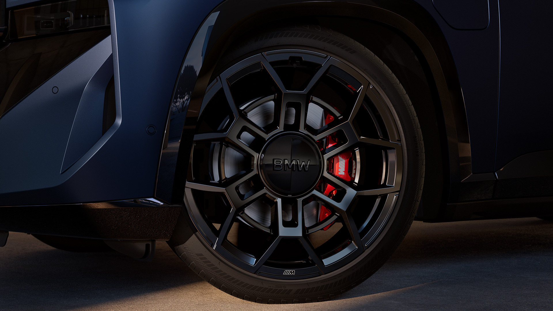 Close-up of a BMW car&#x27;s front wheel and tire, showcasing the intricate black alloy rim design with visible red brake calipers.
