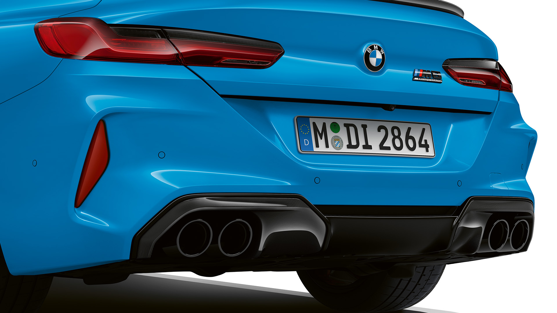Rear view of a blue BMW car featuring dual exhaust pipes and sleek taillights.