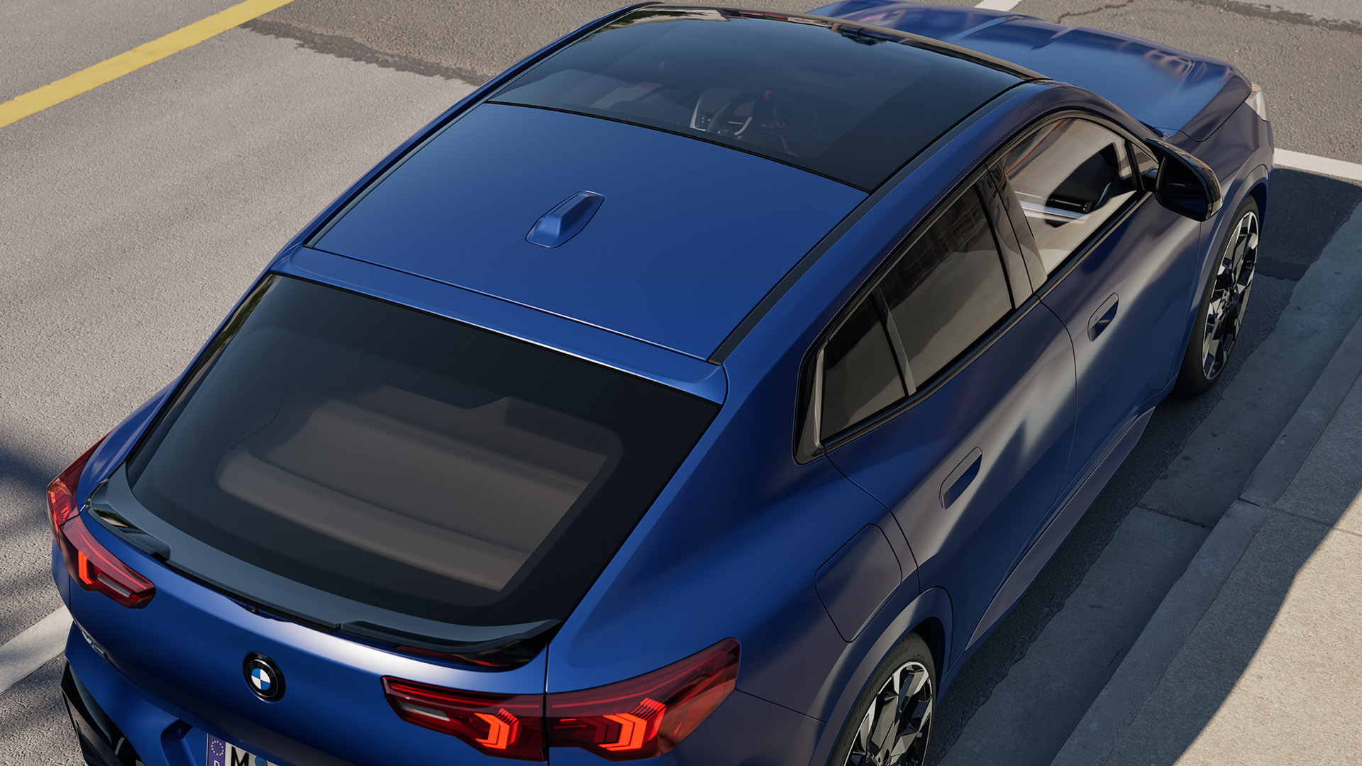 Overhead view of a blue BMW car parked on the side of a street, showing its sunroof and rear design.
