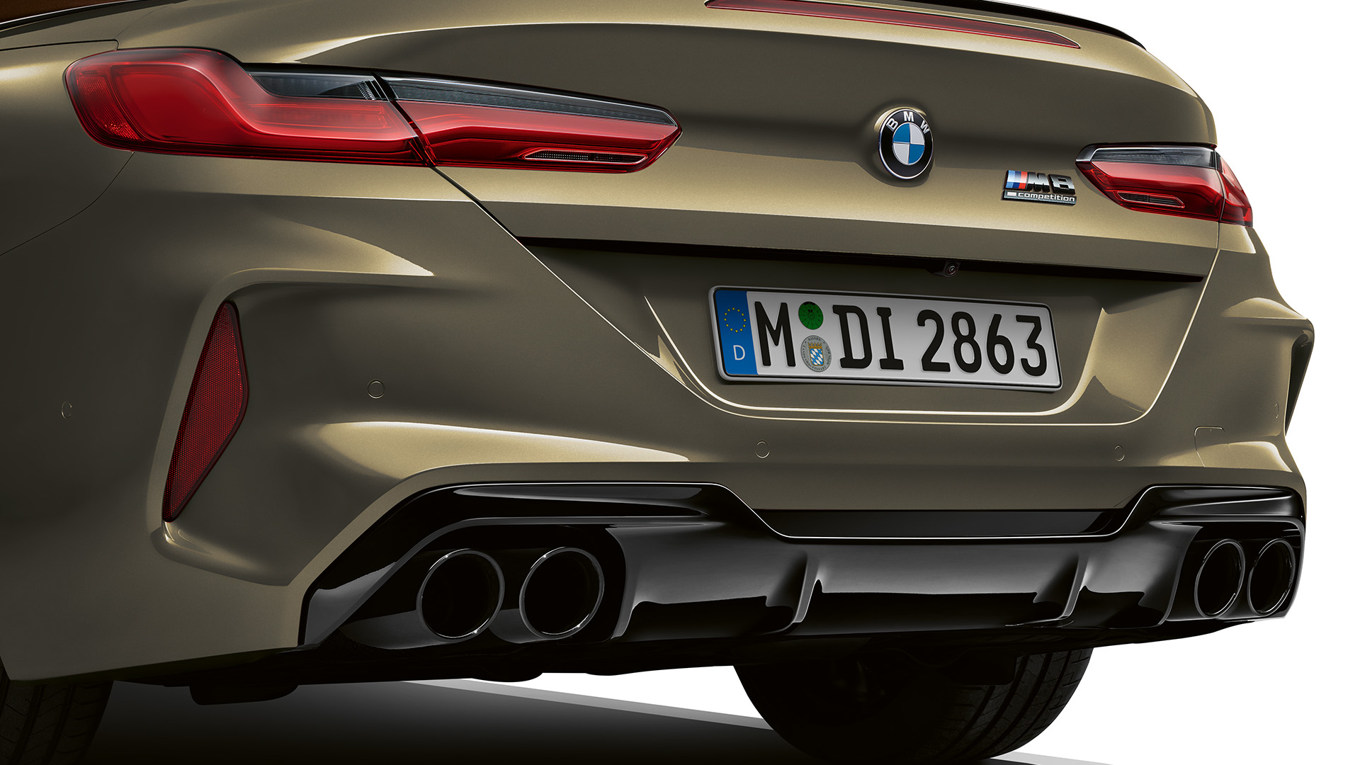Rear view of a beige BMW car featuring dual exhaust pipes and the BMW logo.