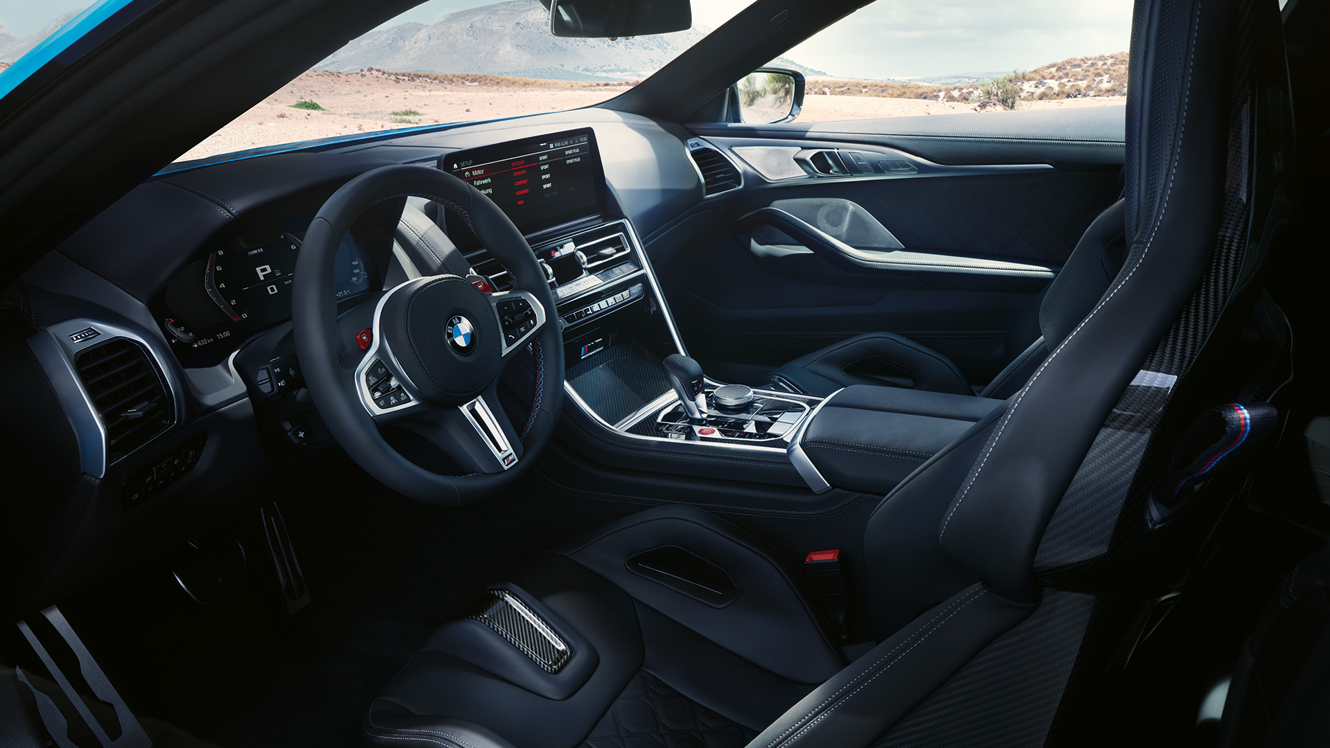 Interior view of a modern BMW car showcasing the steering wheel, dashboard, center console, and front seats with a scenic desert landscape visible through the windows.