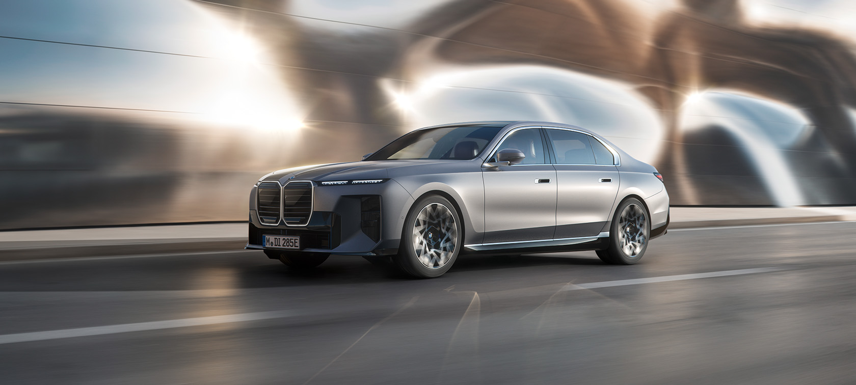 Front left side of a BMW i7 on the road with the waved mirror in the background
