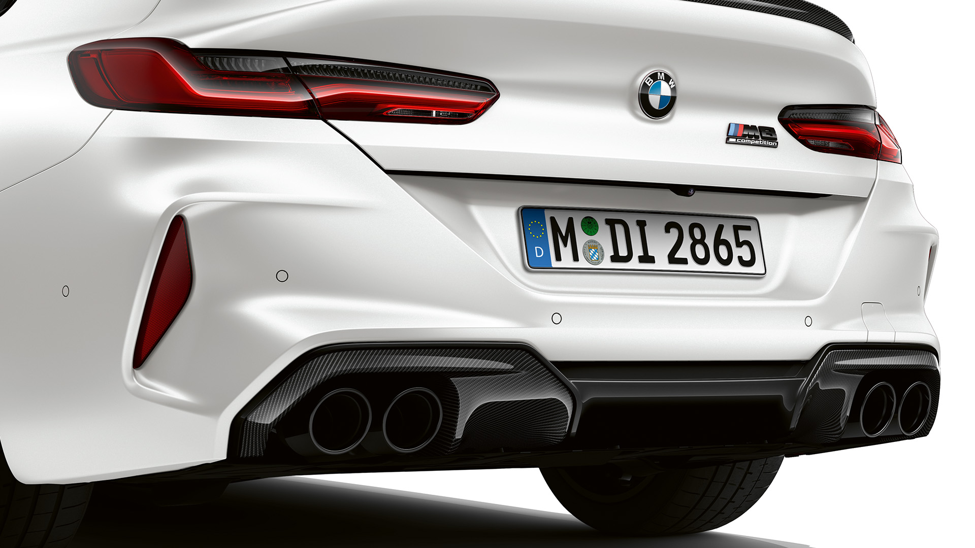 Rear view of a white BMW car featuring dual exhaust pipes and sleek taillights.