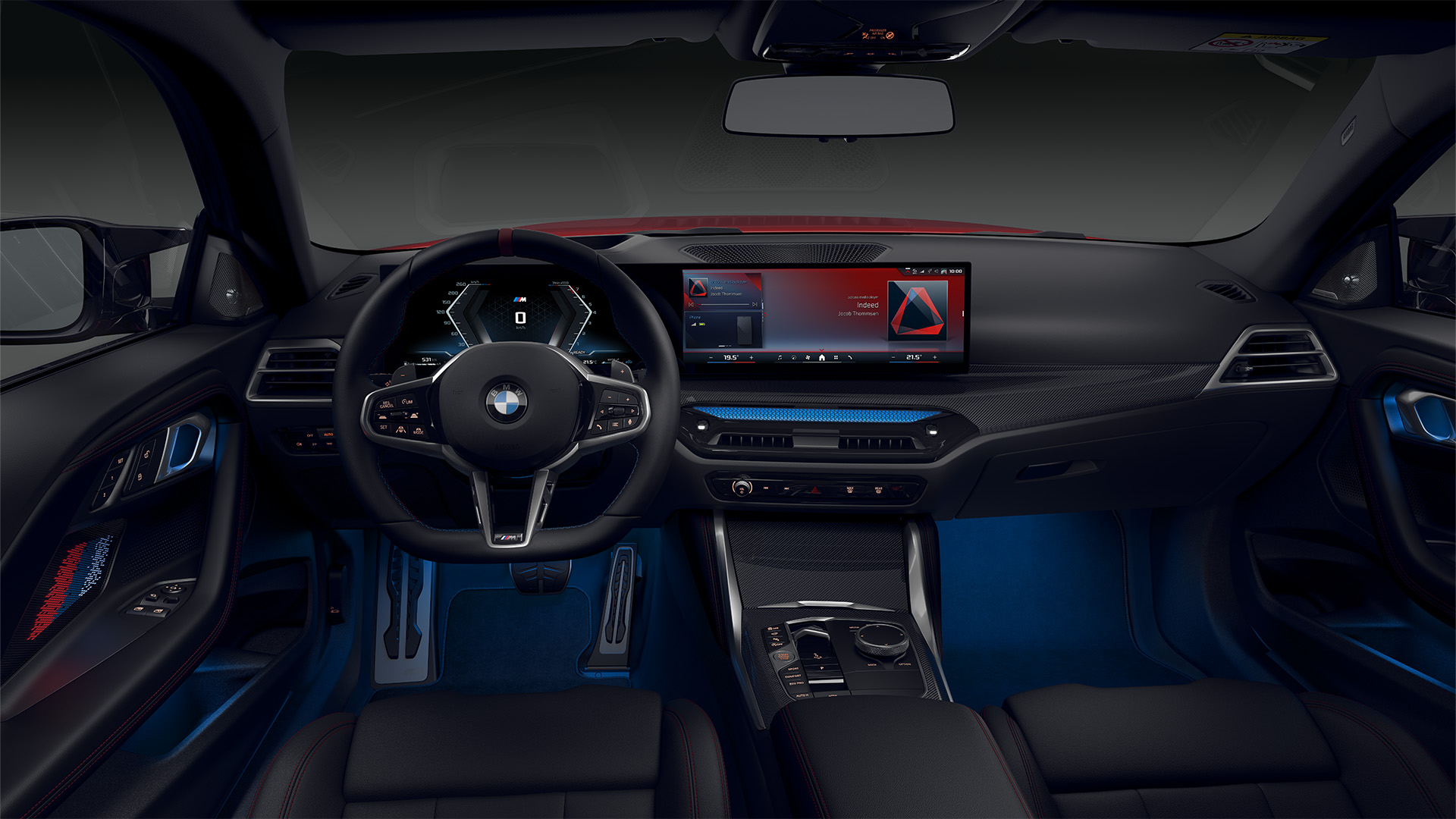 Interior view of a modern BMW car showing the steering wheel, dashboard, and infotainment system with digital displays.