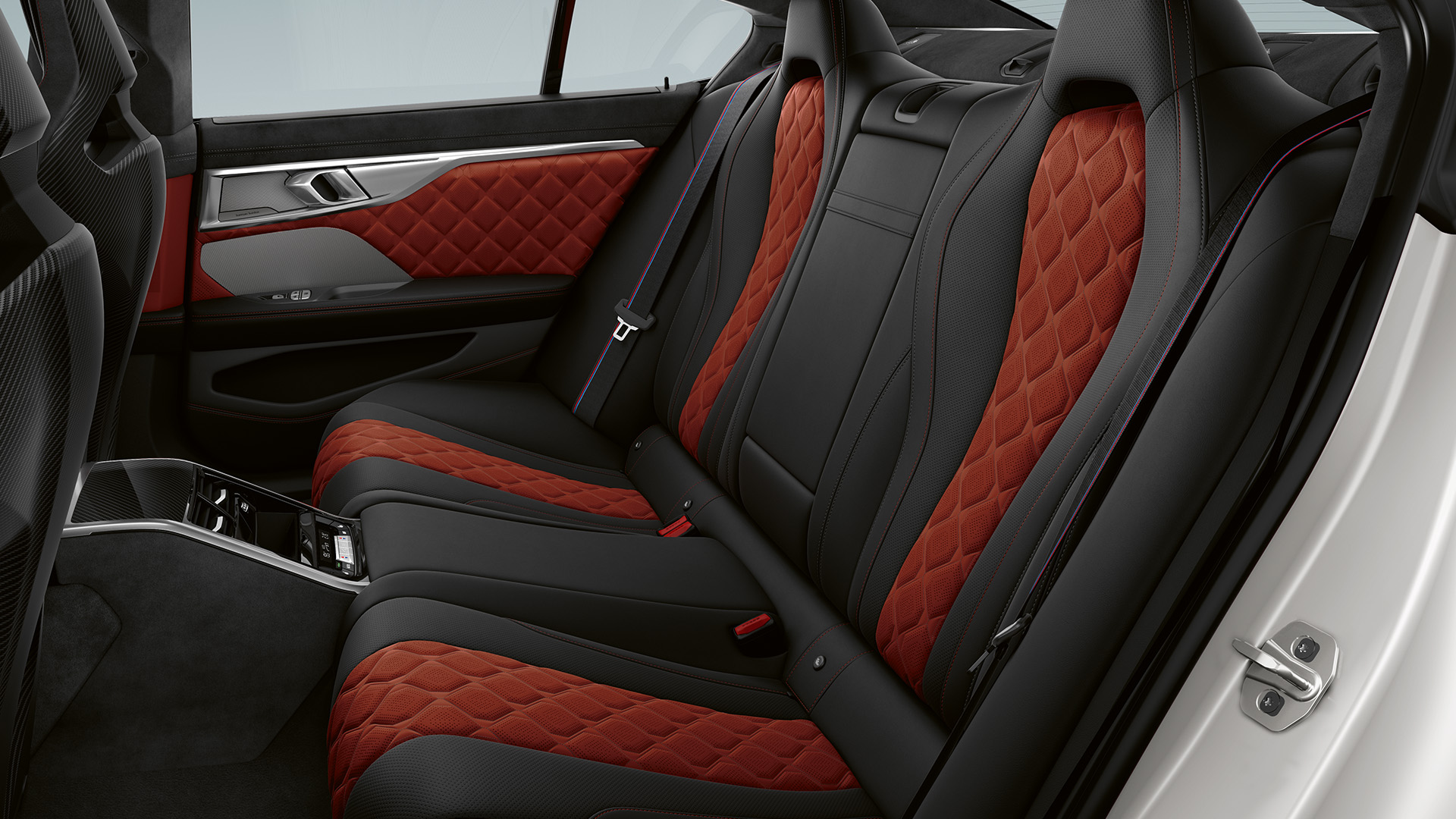Interior of a luxury car showing the back seats with black and red diamond-stitched upholstery, sleek design, and modern features.
