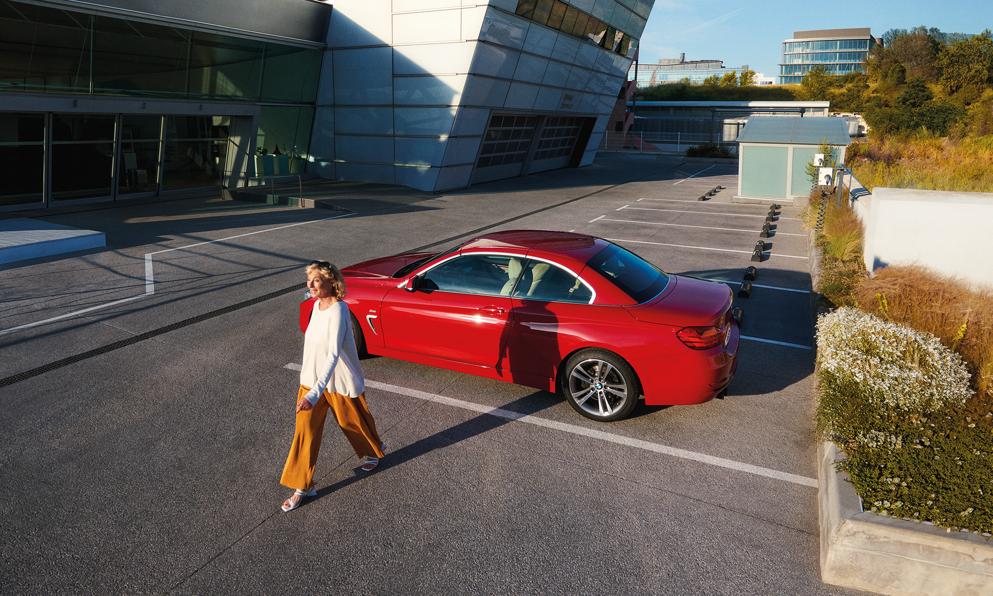 Lady walking by an red BMS Convertible parked outside of the dealership