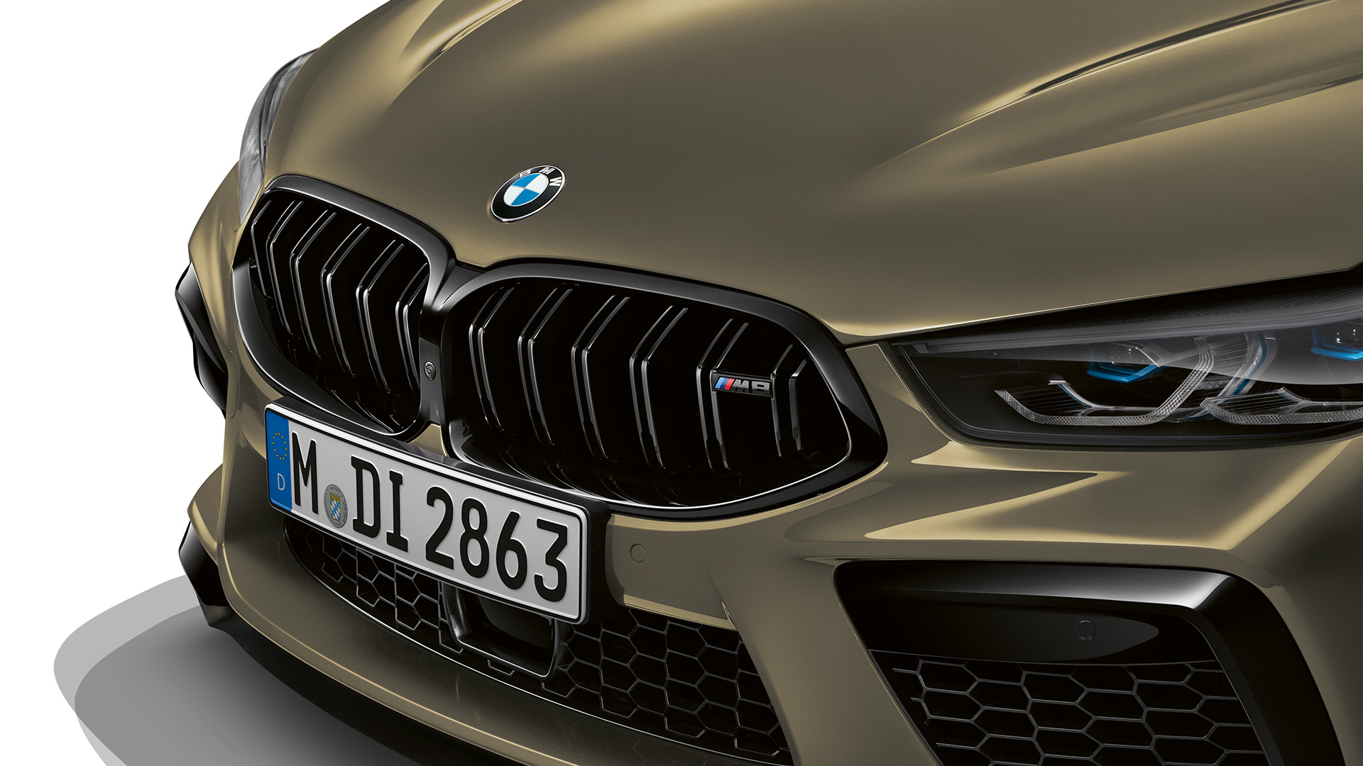 Close-up of a metallic gold BMW M-series car front, featuring kidney grille and sleek headlights.