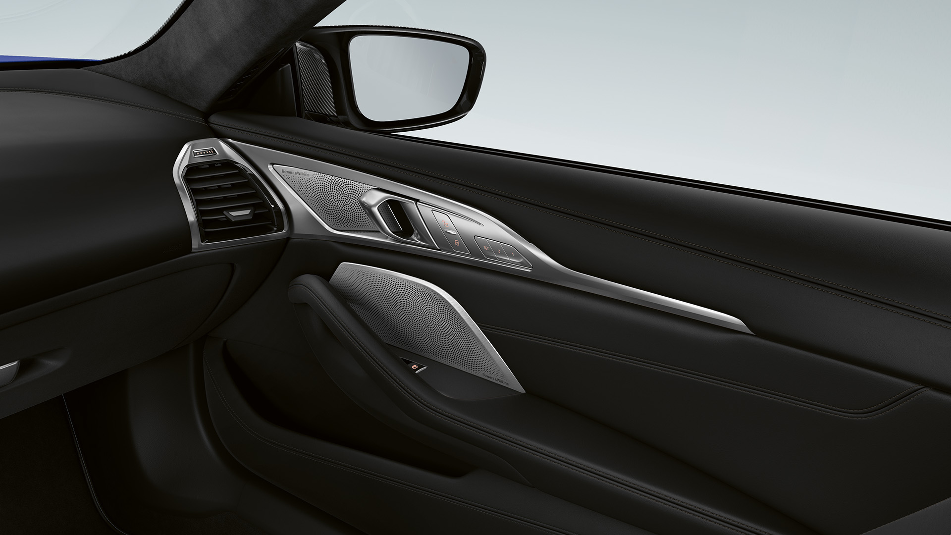 Interior view of a BMW car door showing black leather upholstery, silver trim with intricate patterns, and a side mirror.