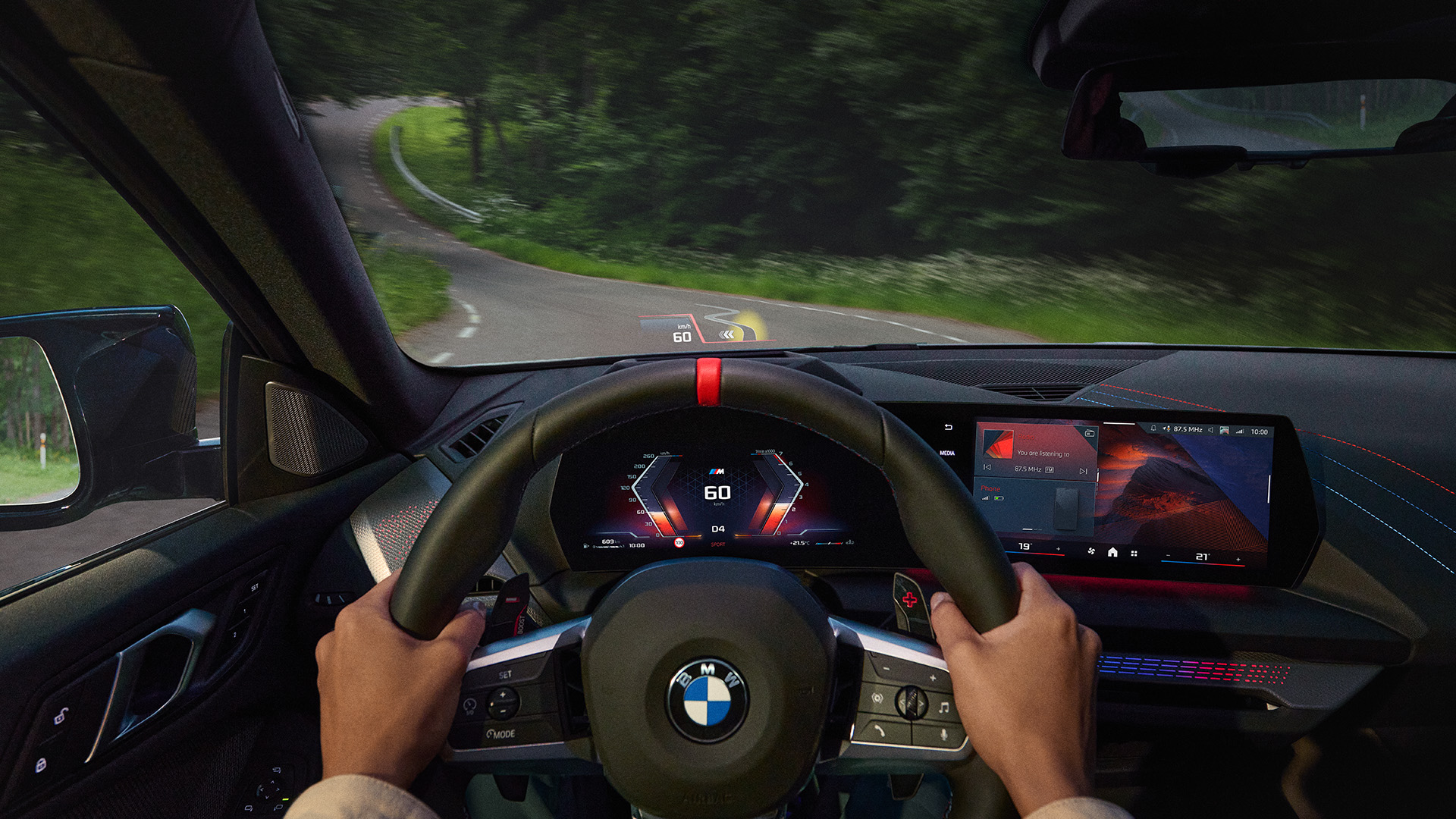Driver's perspective inside a BMW car, showing hands on the steering wheel, digital dashboard displaying 60 km/h speed, and a winding road ahead surrounded by greenery.