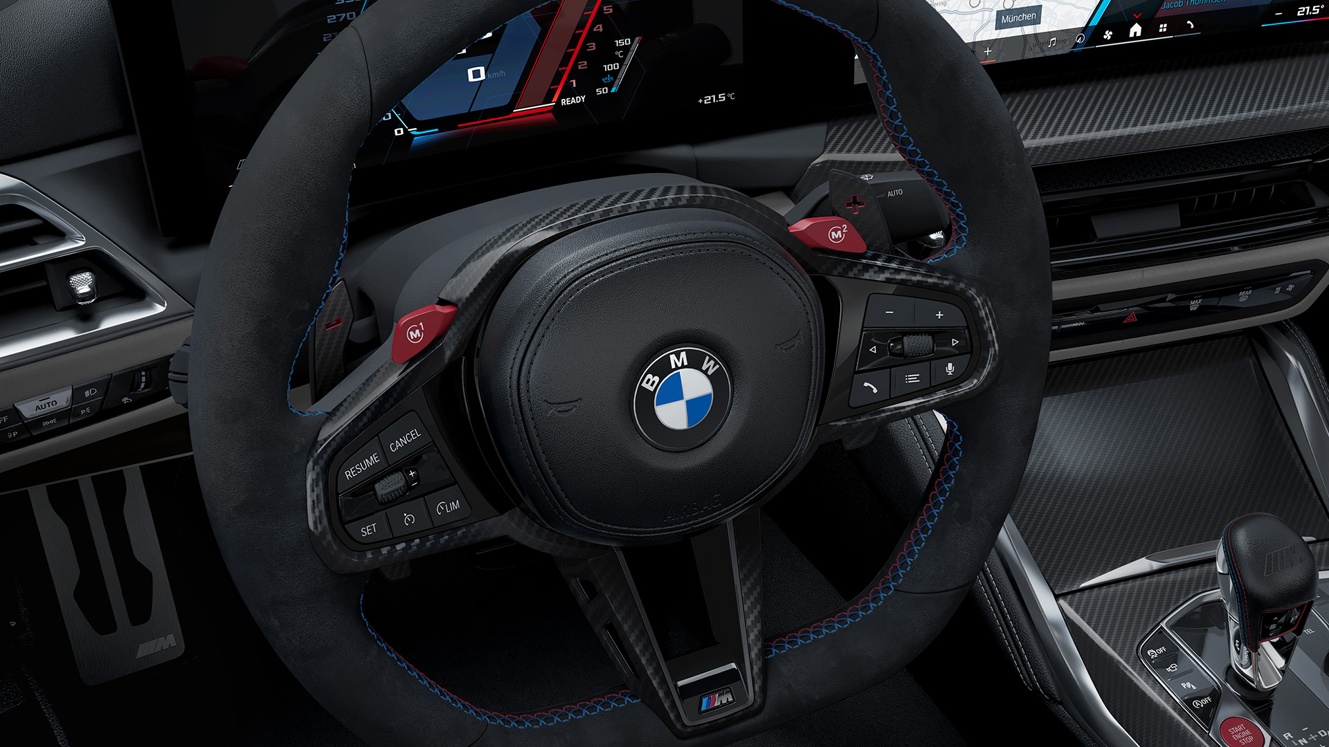 Interior view of a BMW car showing the steering wheel with the BMW logo, dashboard with digital displays, and gear shift.