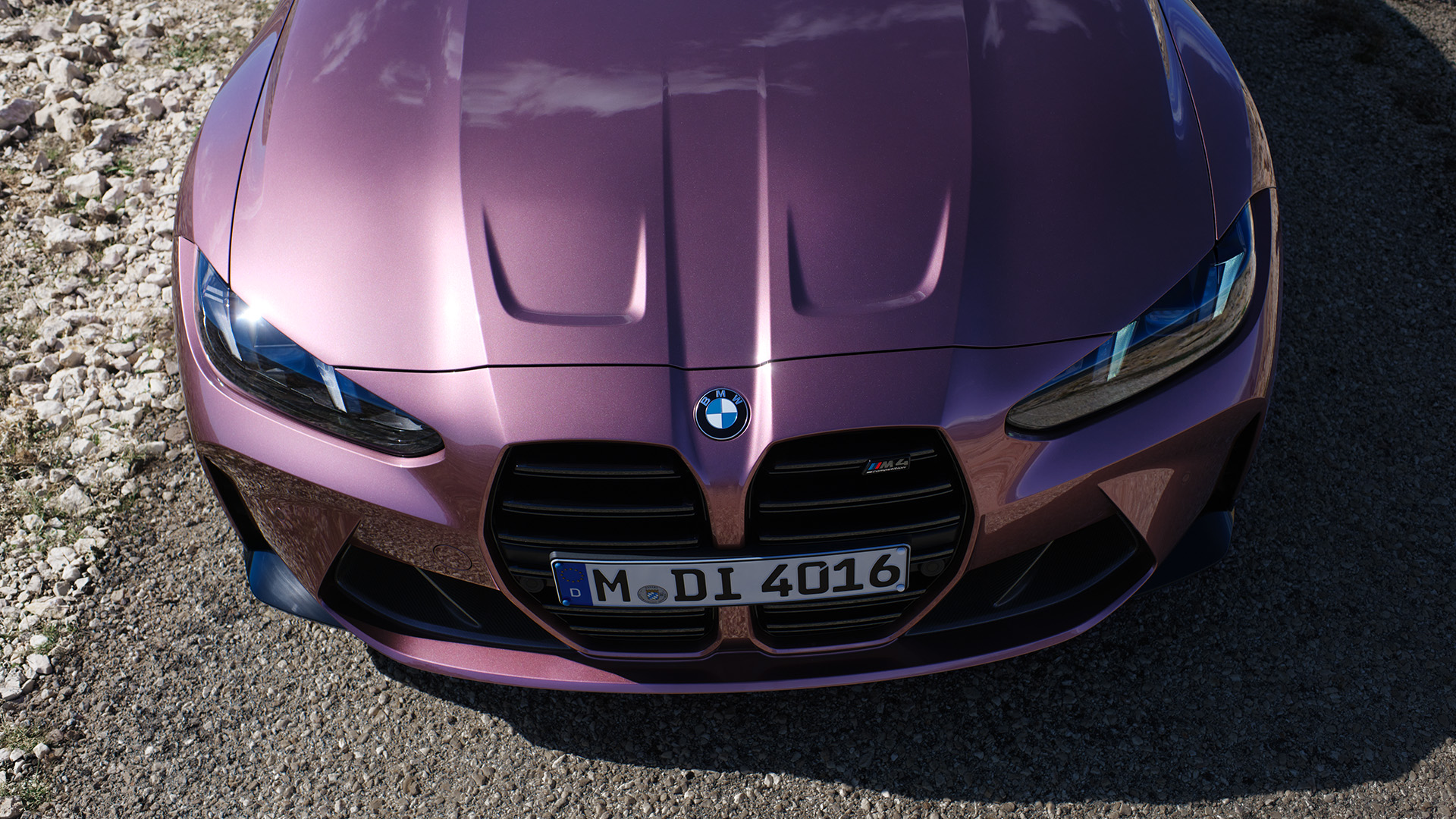 Front view of a purple BMW car parked on a gravel surface.