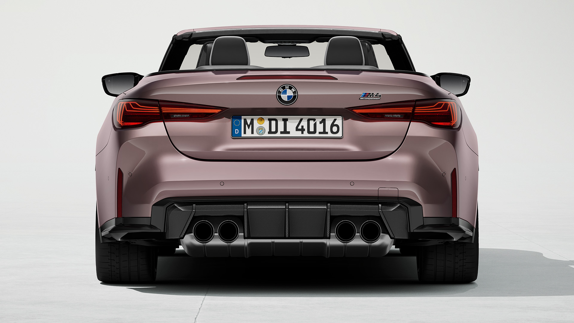 Rear view of a metallic pink BMW convertible, showcasing dual exhaust pipes and sleek design.