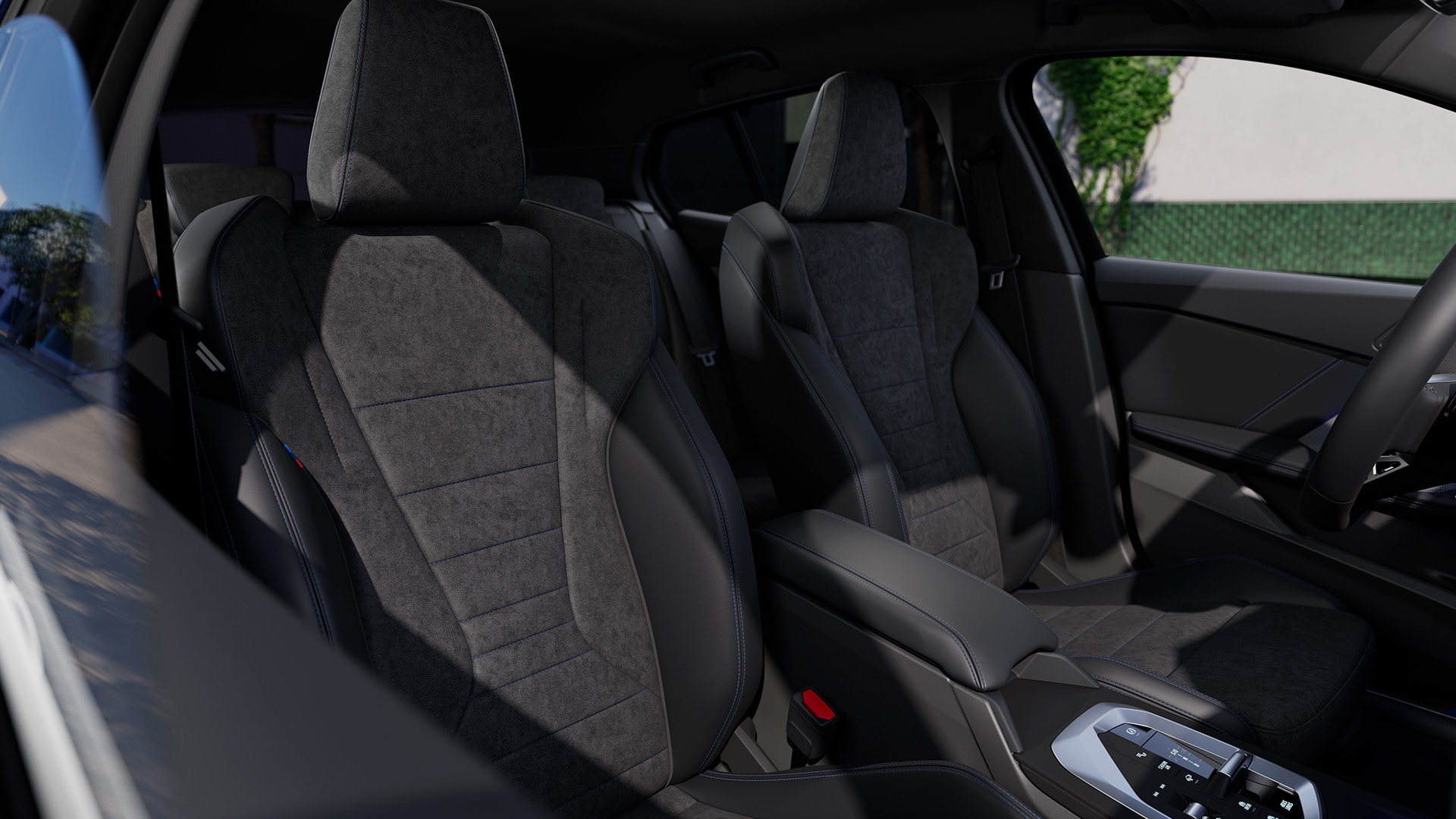 Interior view of a modern car showing the front seats, dashboard, and center console, with greenery visible through the driver's side window.