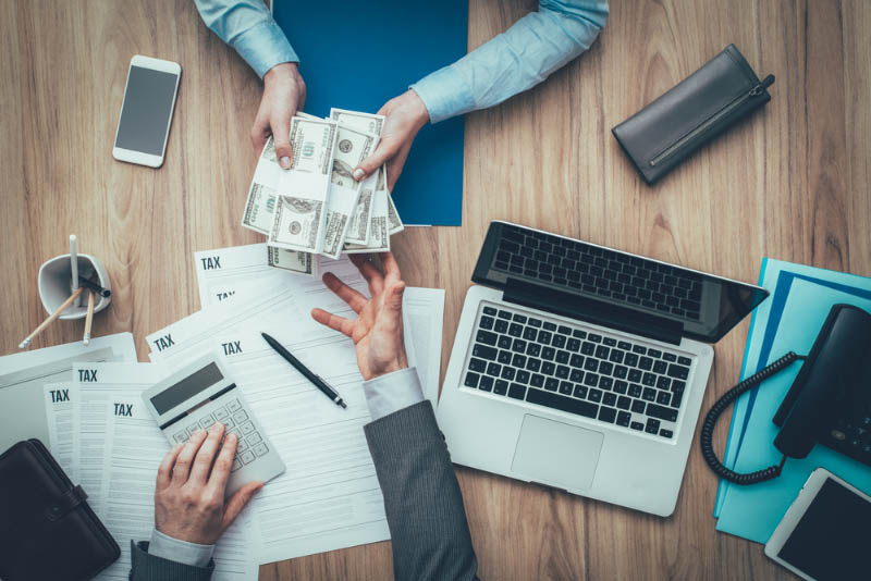 Man handing cash over a pile of tax forms