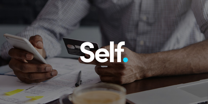 man holding credit card and mobile phone with the self logo in foreground. 